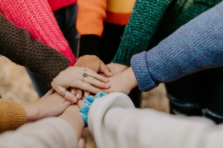 people in a circle all reaching their hands in - ABA Therapy helps you connect.